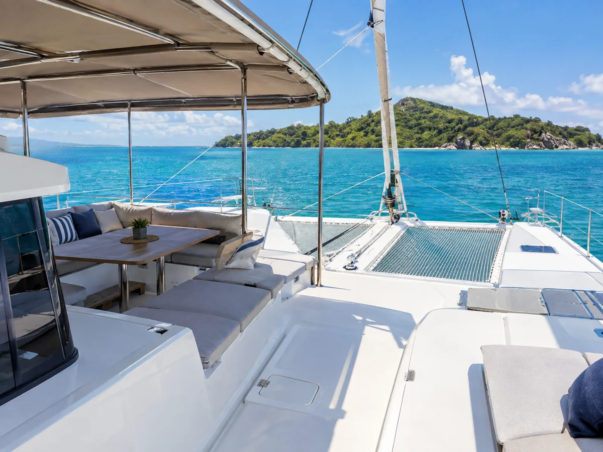 La cubierta abierta de un catamarán de vela con una zona de asientos a la sombra y el mar turquesa